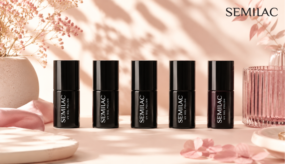 Five Semilac gel polish bottles lined up in a row on a pale pink surface beside dried flowers