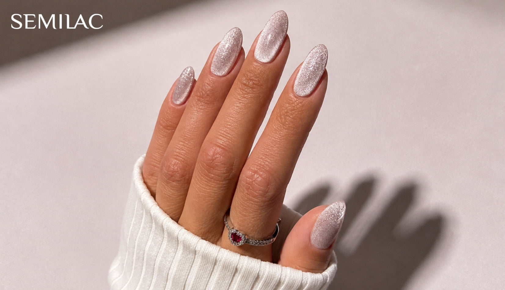 Hand wearing sheer silvery cat eye gel polish, with a soft line of light running down each almond-shaped nail