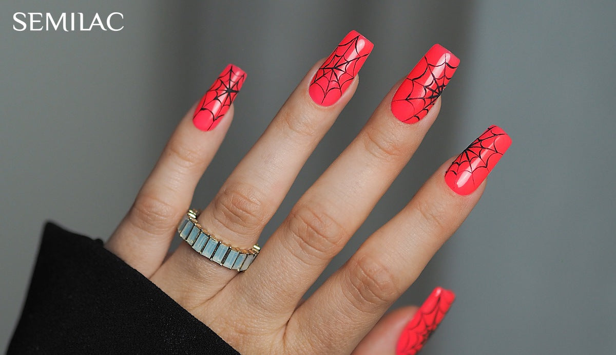 Neon coral gel nails with fine black spider web nail art on a grey background